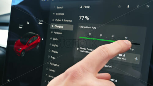 Video - Chisinau, Moldova - January 23, 2024: Male hands setting the charge limit and the charge current of the red Tesla Model 3 electric car. Dark theme