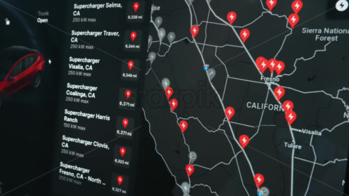 Video - Chisinau, Moldova - January 23, 2024: Charging locations list represented by corresponding pins on the map on the touch screen of the red Tesla Model 3 electric car. Dark theme