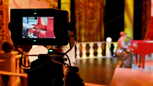 Video - Professional camera filming a woman playing a red piano on the backstage of a TV set