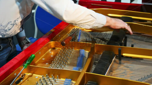 Video - Close up of a man fixing a red piano