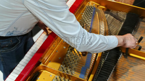 Video - Close up of a man fixing a red piano
