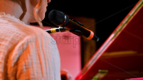 Video - Woman singing into the microphone and playing a red piano