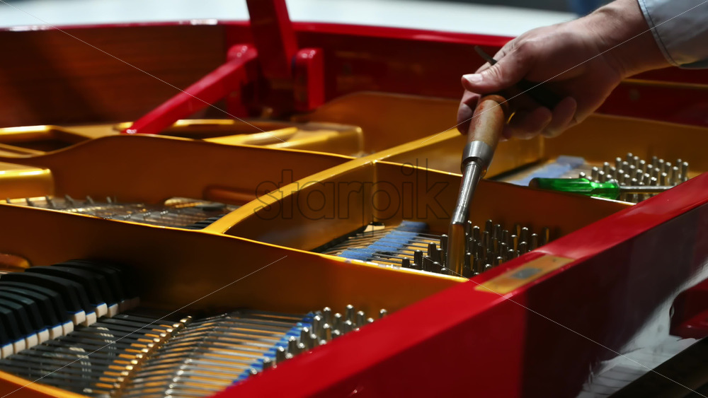 Video - Close up of a man fixing a red piano