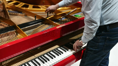 Video - Close up of a man fixing a red piano