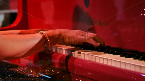Video - Close-up of an elderly woman playing a red piano