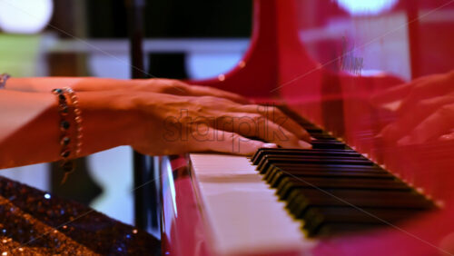 Video - Close-up of an elderly woman playing a red piano