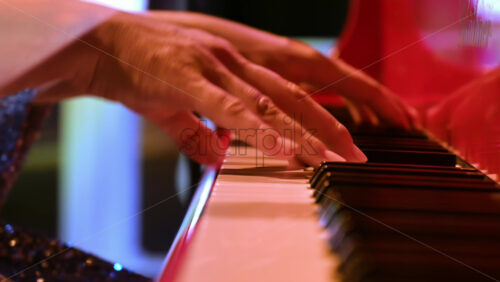 Video - Close-up of an elderly woman playing a red piano