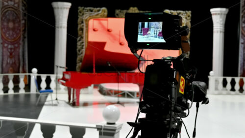 Video - Professional camera filming a red piano on the backstage of a TV set