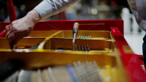 Video - Close up of a man fixing a red piano