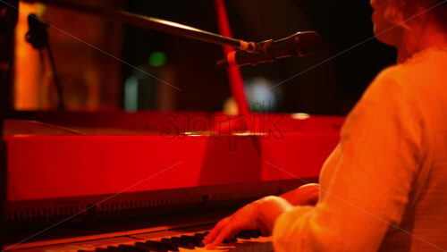 Video - Woman singing into the microphone and playing a red piano