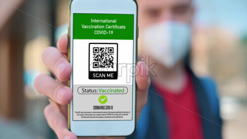 Video - Man in medical mask showing an International Vaccination Certificate COVID-19 QR code on smartphone