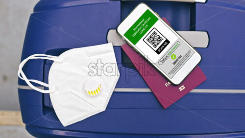 Video - Passport and smartphone with International Vaccination Certificate COVID-19 QR code on suitcase with mask