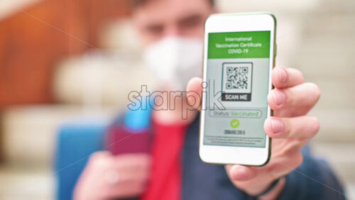 Video - Man in medical mask showing an International Vaccination Certificate COVID-19 QR code on smartphone