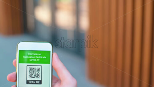 Video - Male hand holding a smartphone with International Vaccination Certificate COVID-19 QR code