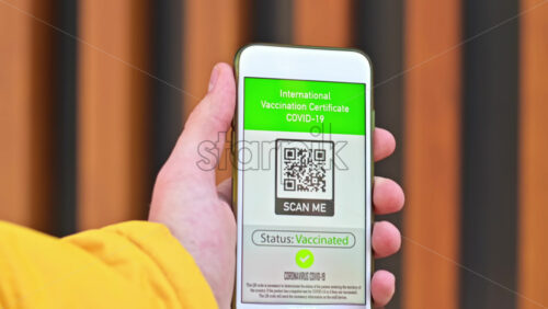 Video - Male hand holding a smartphone with International Vaccination Certificate COVID-19 QR code