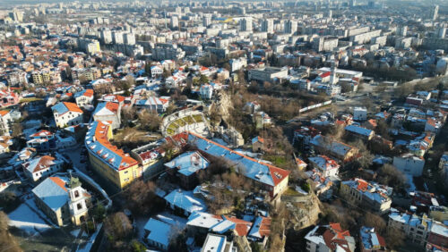 Video - Aerial drone view of the ancient Theatre of Philippopolis. Orange roofs covered in snow. The city center of Plovdiv, Bulgaria