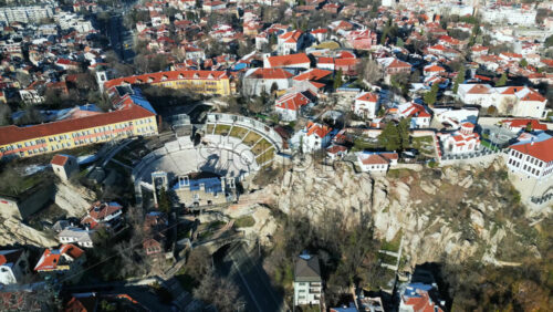 Video - Aerial drone view of the ancient Theatre of Philippopolis. Orange roofs covered in snow. The city center of Plovdiv, Bulgaria