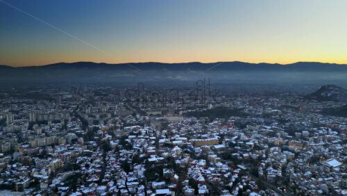 Video - Aerial drone panoramic view of Plovdiv city covered in snow at sunset. Bulgaria