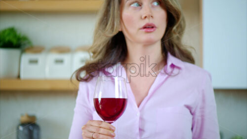 Video - Woman getting a headache while hildong a glass of red wine in the kitchen