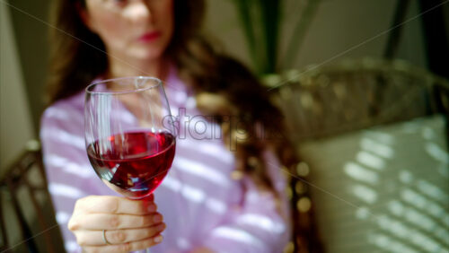 Video - Woman swirling a glass of red wine in daylight
