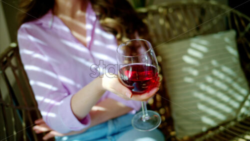 Video - Woman swirling a glass of red wine in daylight
