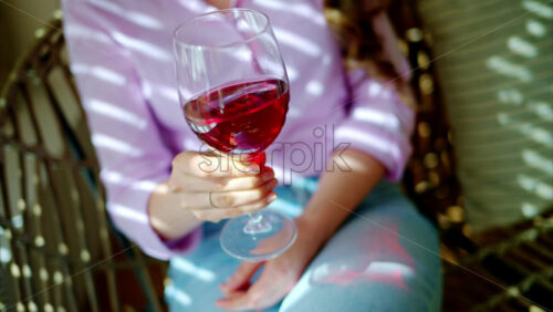 Video - Woman swirling a glass of red wine in daylight