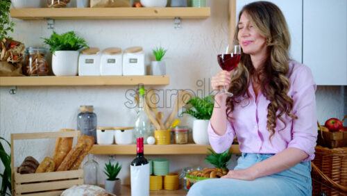 Video - Woman enjoying a glass of red wine in the kitchen