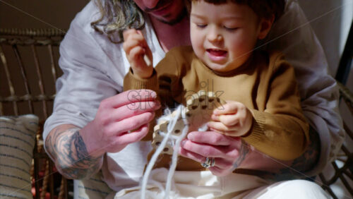 Video - Father playing with his son with ecological wooden toys on a day bed