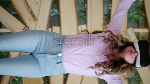 Video - Woman looking through VR headset and jumping on bed. Vertical