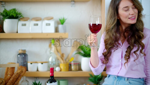Video - Woman drinking a glass of red wine and dancing in the kitchen