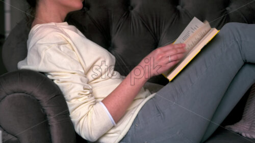Video - Caucasian woman sitting on a chair and reading a book