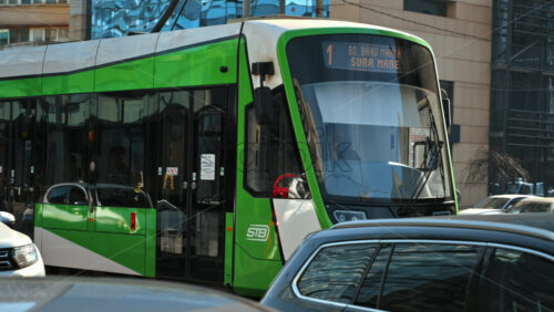 Video - Bucharest, Romania - March 02, 2024: Modern tram and riding cars on the street. Panoramic view. Electric and ecological public transport