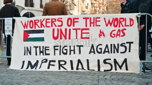 Video - Bucharest, Romania - March 02, 2024: Propaganda poster against militarization and imperialism with people behind it. Supporting the Palestinian people