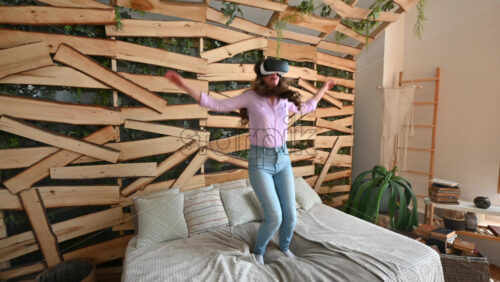 Video - Woman looking through VR headset and jumping on bed