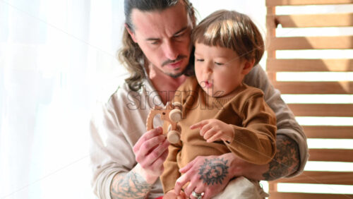 Video - Father playing with his son with ecological wooden toy near a window