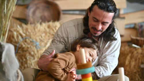 Video - Father playing with his son in a barn, near square hay bales