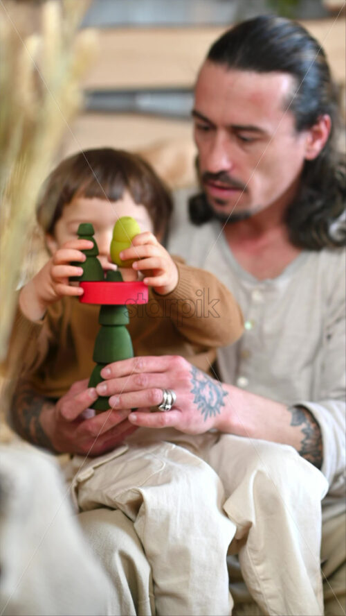 Video - Father playing with his son with colourful, ecological wooden toys in a barn, near square hay bales