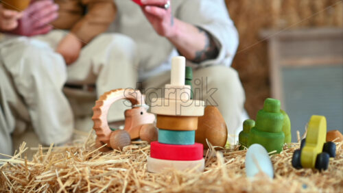 Video - Father playing with his son with colourful, ecological wooden toys in a barn, near square hay bales