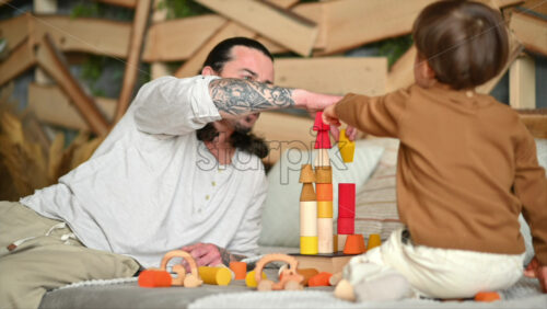 Video - Father playing with his son with colourful, ecological wooden toys on the bed