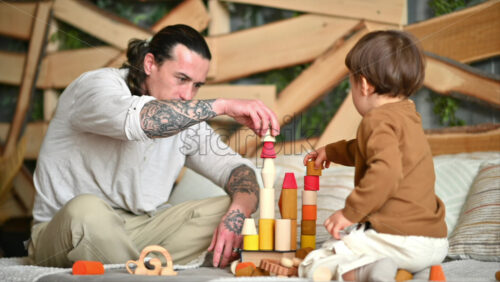 Video - Father playing with his son with colourful, ecological wooden toys on the bed