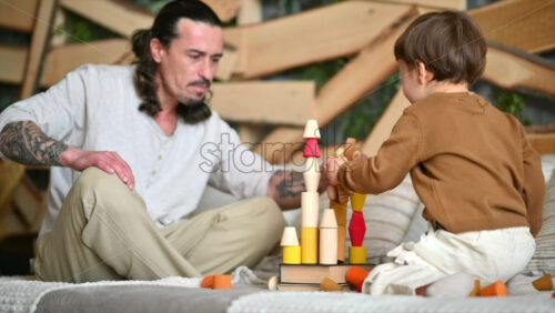Video - Father playing with his son with colourful, ecological wooden toys on the bed