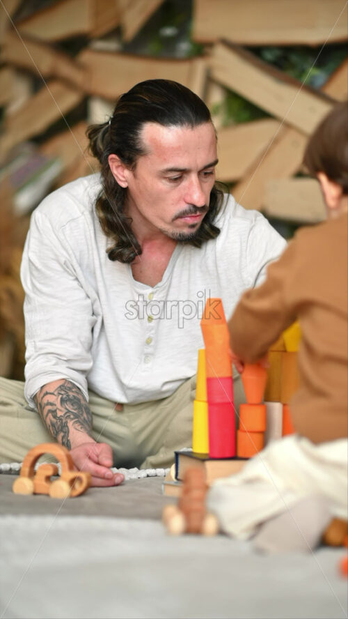 Video - Father playing with his son with colourful, ecological wooden toys on the bed