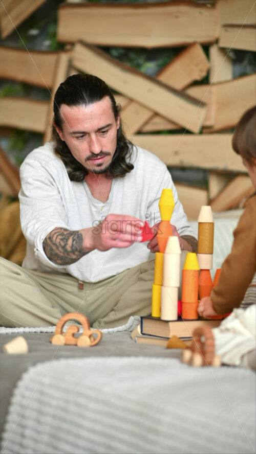 Video - Father playing with his son with colourful, ecological wooden toys on the bed