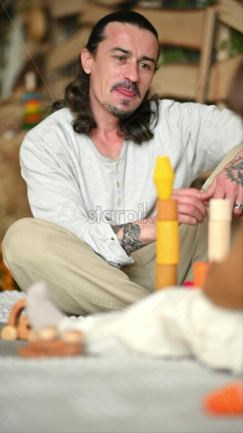 Video - Father playing with his son with colourful, ecological wooden toys on the bed