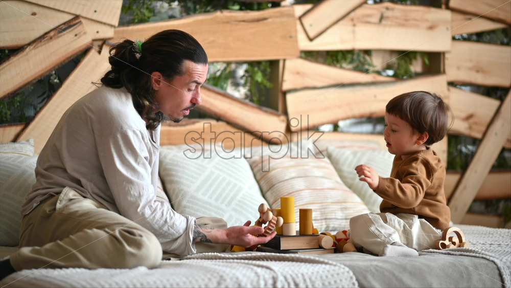 Video - Father playing with his son with colourful, ecological wooden toys on the bed