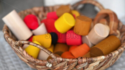 Video - Father playing with his son with colourful, ecological wooden toys from a basket on the bed