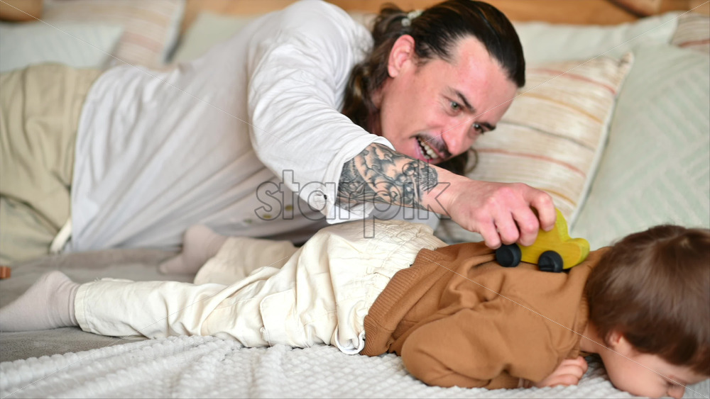 Video - Father playing with his son with colourful, ecological wooden toys on the bed