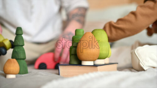 Video - Father playing with his son with colourful, ecological wooden toys on the bed