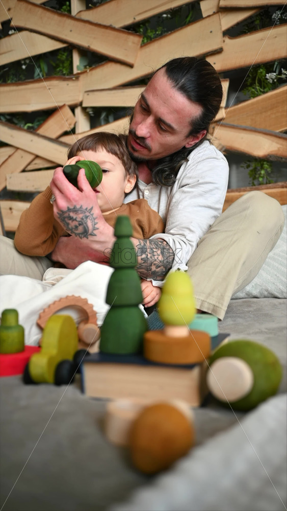 Video - Father playing with his son with colourful, ecological wooden toys on the bed. Vertical