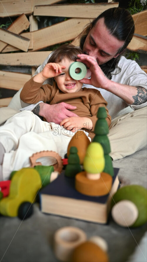 Video - Father playing with his son with colourful, ecological wooden toys on the bed. Vertical